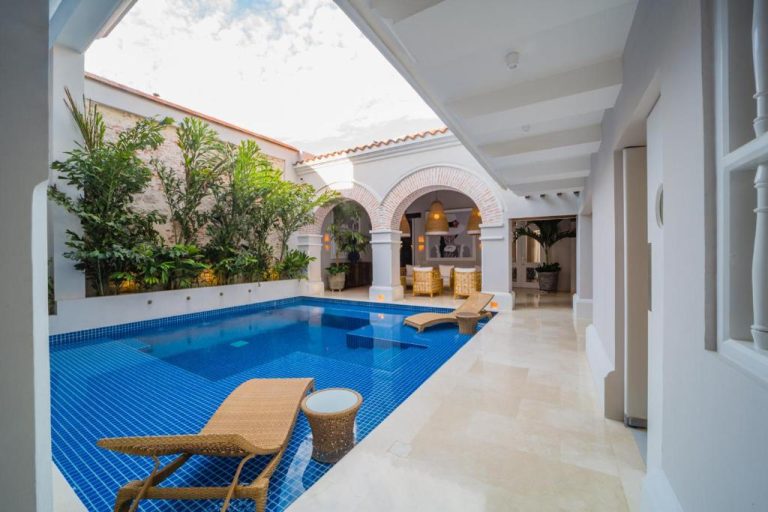 Piscina interior con patio colonial y tumbonas de ratán en Casa La Merced by Mustique, Cartagena