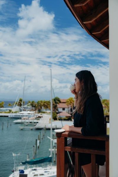 Mujer tomando café en terraza con vistas al puerto deportivo del The Bannister Hotel & Yacht Club