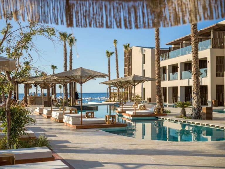 Piscina exterior con tumbonas y parasoles de palma en Nalu Resort & SPA Adults Only con vistas al mar