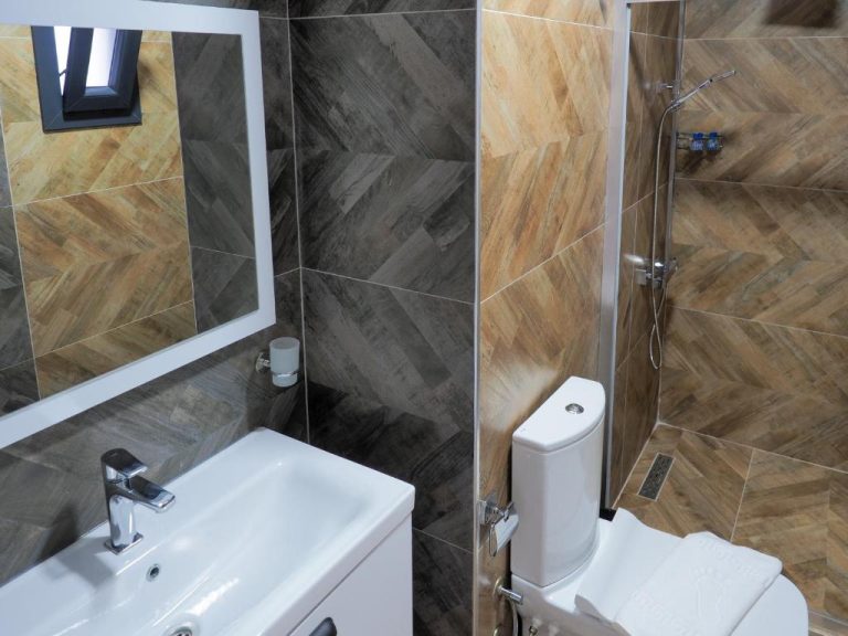 Baño moderno con ducha, inodoro y lavabo en el Hotel Oliva Mare con azulejos decorativos