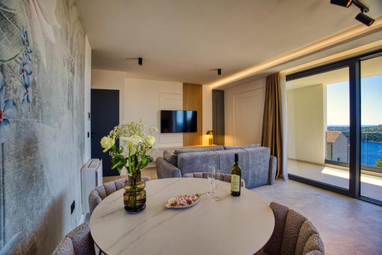 Salón comedor moderno con vistas al mar y botella de vino en La Dolce Villa 1