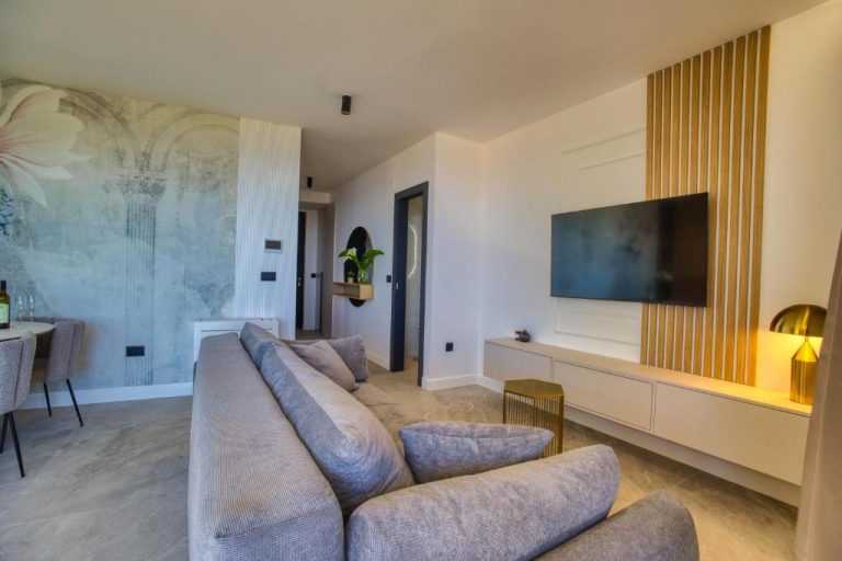 Salón moderno con sofá gris y televisión en pared de madera del apartamento La Dolce Villa 1