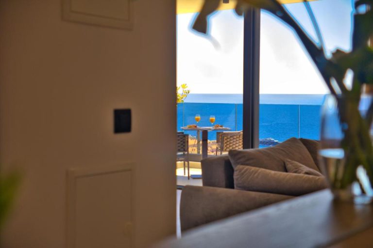 Salón con terraza y vistas al mar azul en La Dolce Villa 1, con desayuno y zumos en la mesa exterior