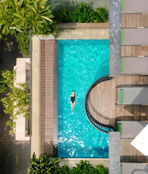 Vista aérea de la piscina exterior del GM Premium Hotel con agua turquesa y zona de madera