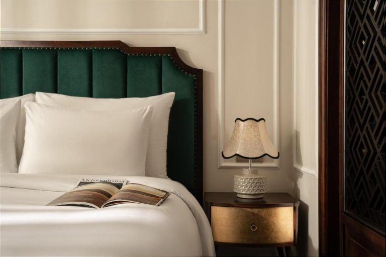 Habitación de lujo con cabecero de terciopelo verde y mesita dorada en GM Premium Hotel