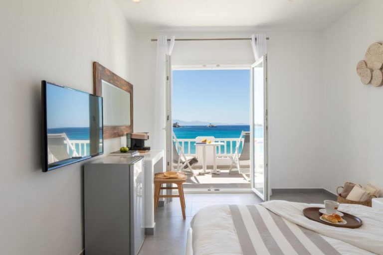 Habitación con cama doble y balcón con vistas al mar turquesa en Acrogiali Beachfront Hotel Mykonos