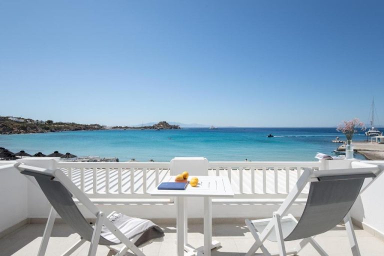 Terraza con sillas blancas y vistas al mar turquesa en Acrogiali Beachfront Hotel Mykonos