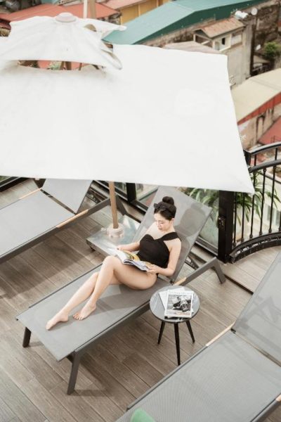 Mujer leyendo en tumbona en la terraza solarium del GM Premium Hotel con vistas a la ciudad