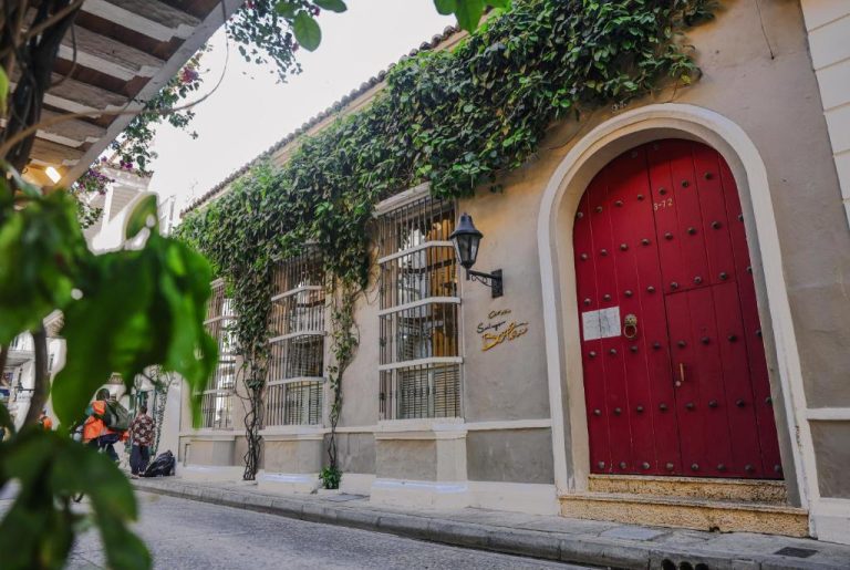 Fachada colonial con puerta roja y enredaderas del Hotel Casa Santiago Botero en Cartagena