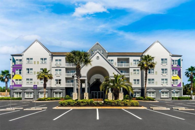 Fachada exterior del Spark by Hilton Panama City Beach con palmeras y amplio aparcamiento