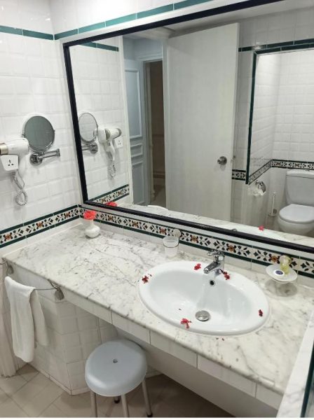 Baño clásico con encimera de mármol y lavabo del Hotel Soussana con espejo grande y detalles decorativos
