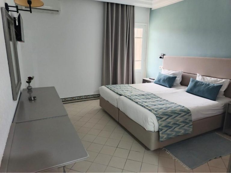 Habitación doble con cama matrimonial y almohadas azules en Hotel Soussana