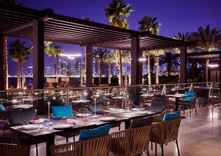 Terraza exterior del restaurante del InterContinental Doha Beach & Spa con vistas al skyline nocturno de Doha