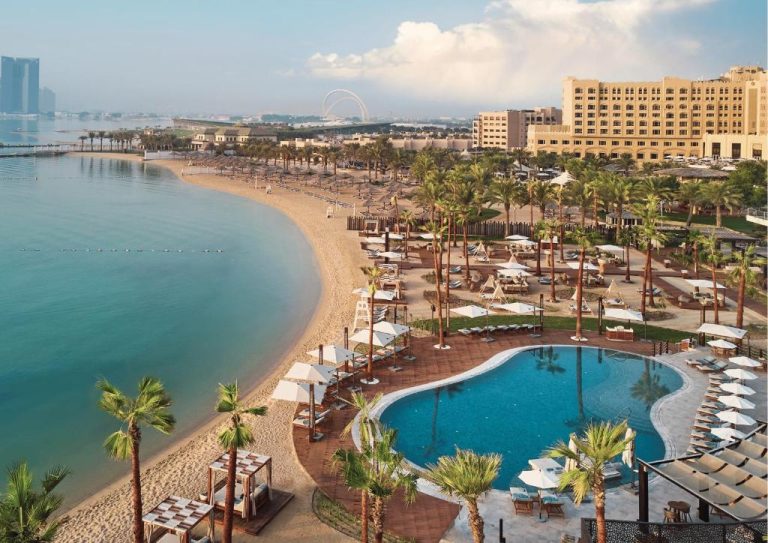 Piscina exterior y playa privada del InterContinental Doha Beach & Spa con palmeras y tumbonas