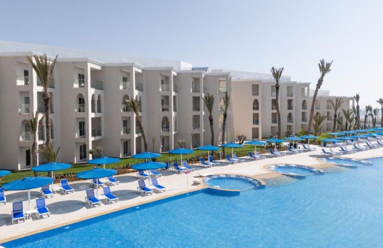 Piscina exterior con tumbonas y sombrillas azules del Pickalbatros Palais Des Roses Agadir All Inclusive
