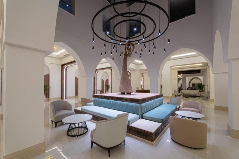 Lujoso lobby con escultura central y sofás turquesa en Pickalbatros Palais Des Roses Agadir