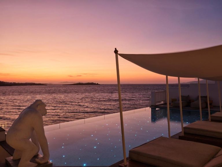Piscina infinita con luces estrelladas y vistas al mar al atardecer en Icon Mykonos