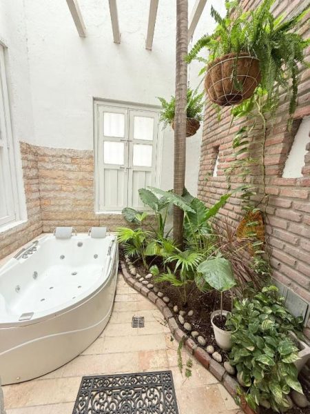 Jacuzzi privado con jardín tropical interior en Hotel Boutique Don Pepe, rodeado de plantas y paredes de ladrillo