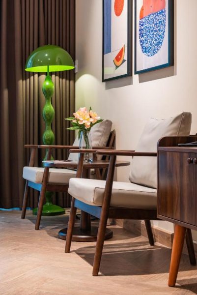 Salón elegante con sillones de madera y lámpara de pie verde en Anise Luxe Home