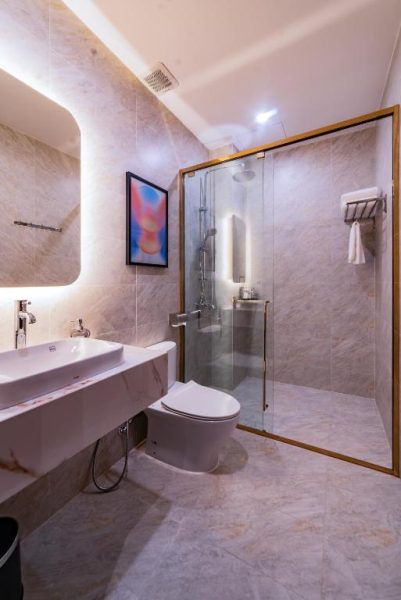 Baño moderno con ducha de cristal y revestimiento de mármol en Anise Luxe Home