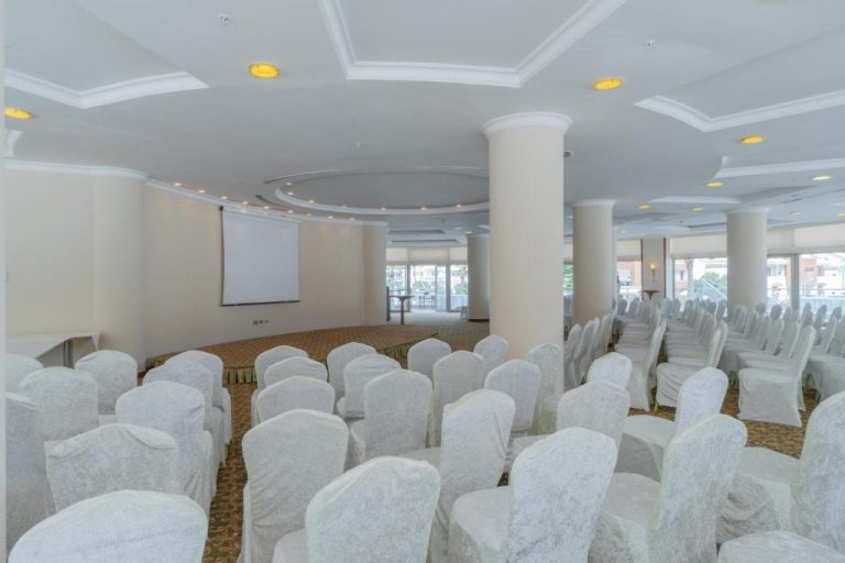 Sala de conferencias con sillas blancas y pantalla de proyección en Pineta Park Deluxe Hotel All Inclusive
