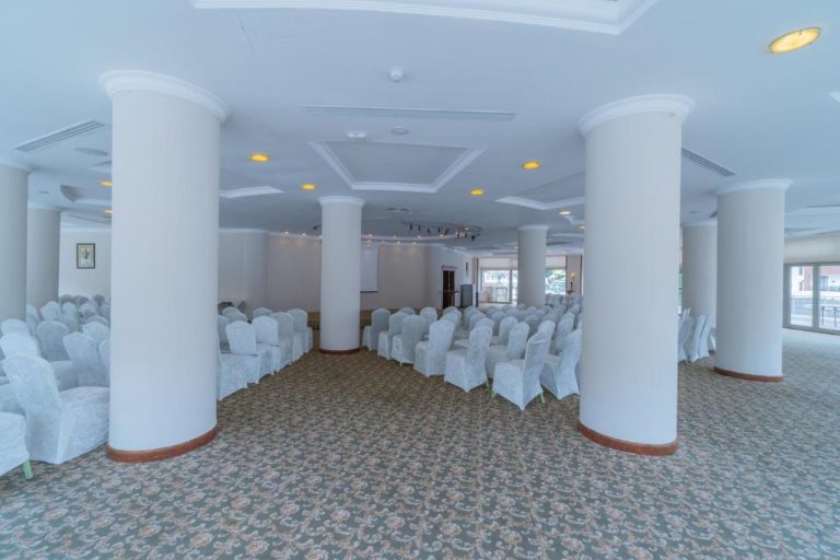 Amplio salón de conferencias con sillas blancas y columnas del Pineta Park Deluxe Hotel All Inclusive