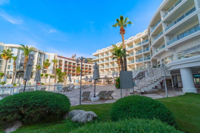 Piscina exterior con tumbonas y palmeras del Pineta Park Deluxe Hotel All Inclusive en Marmaris