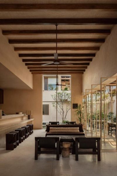 Lobby con vigas de madera y ventilador de techo del NABOA Hotel Tulum con mobiliario rústico