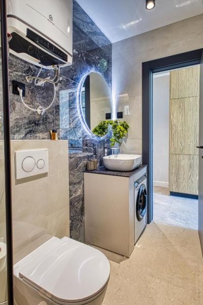 Baño moderno con lavadora integrada, espejo LED y sanitario suspendido en La Dolce Villa 1
