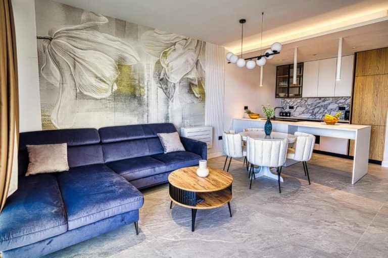 Salón moderno con sofá azul y cocina abierta en La Dolce Villa 1, decoración elegante y contemporánea