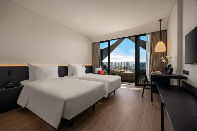 Habitación twin con camas individuales y balcón con vistas a la ciudad en Caro Premium Danang Hotel