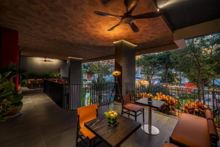 Terraza lounge con mesas y sillas naranjas y vistas nocturnas a la ciudad en Caro Premium Danang Hotel