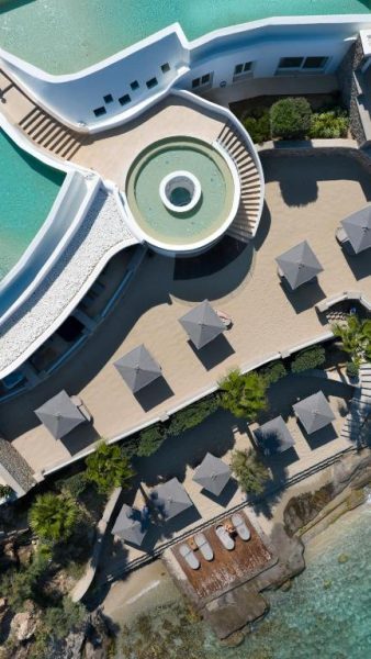 Vista aérea de la terraza con piscina circular y sombrillas del Anax Resort and Spa junto al mar