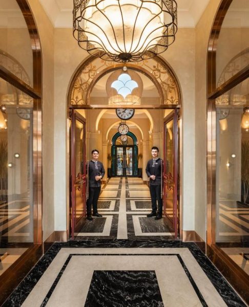 Elegante entrada del Grand Hotel du Lac Boutique Saigon con porteros uniformados y suelo de mármol