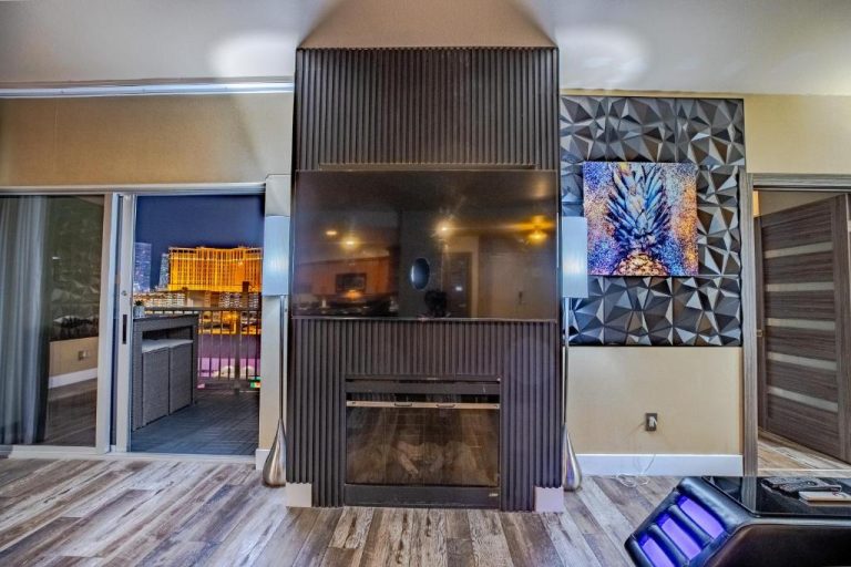 Sala de estar con chimenea y TV del Penthouse Suite Las Vegas con vistas al Strip iluminado