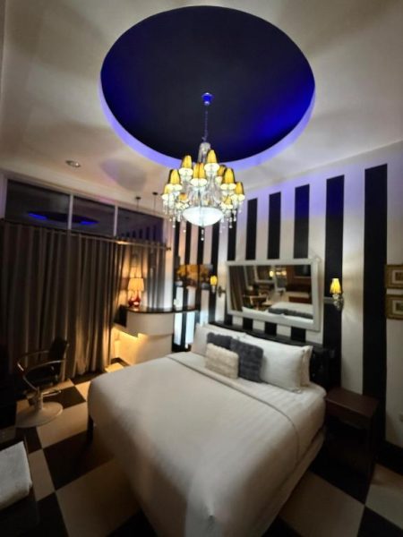Habitación de lujo con lámpara araña y techo azul en Italy Condotel Darasa, decoración elegante en blanco y negro