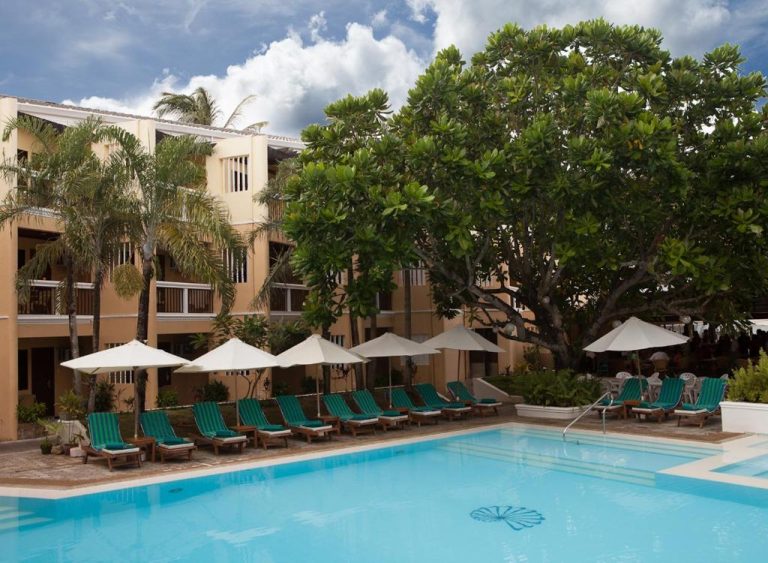 Piscina exterior con tumbonas y sombrillas del Henann Regency Resort and Spa rodeada de palmeras