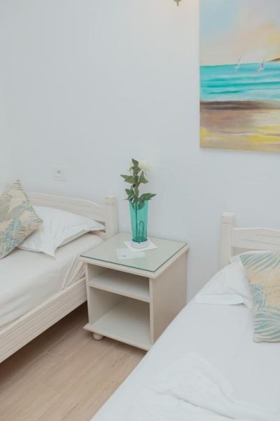 Habitación doble con dos camas individuales y decoración en tonos blancos en Hôtel Résidence Monia
