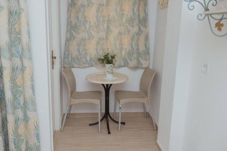 Rincón de terraza interior con mesa redonda y dos sillas en Hôtel Résidence Monia renovado