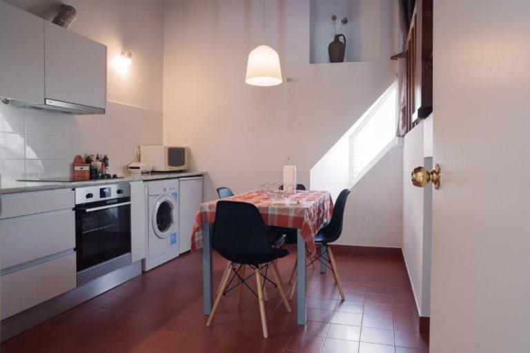 Cocina comedor totalmente equipada con mesa y sillas modernas en Apartamentos da Galé