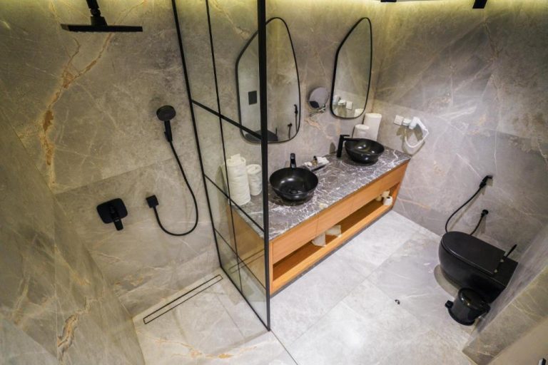 Baño de lujo con doble lavabo negro y ducha de mármol gris en el Hotel Ocean Atlantic View