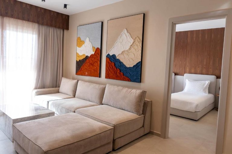 Suite del Ocean Atlantic View con salón moderno, sofá beige y acceso a habitación con cama doble