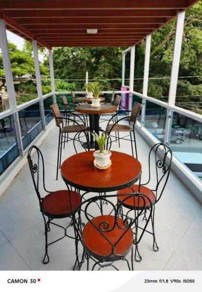 Terraza exterior con mesas y sillas de hierro forjado en EPM Tower Hotel and Events Place