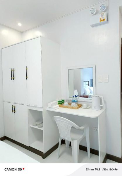 Habitación con escritorio, espejo y armario blanco en EPM Tower Hotel and Events Place