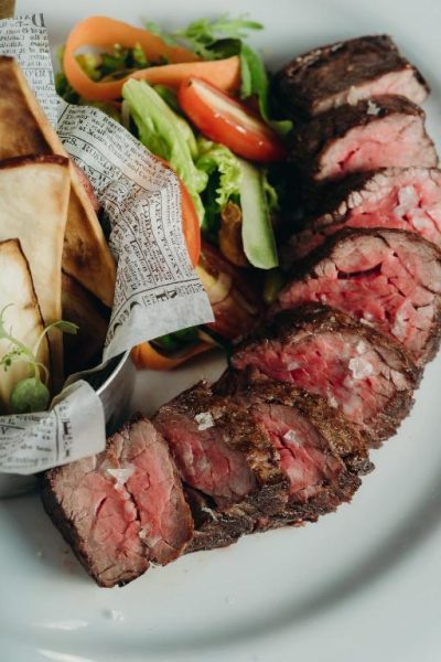 Chuleta de res premium con ensalada fresca y papas fritas en The Bannister Hotel & Yacht Club