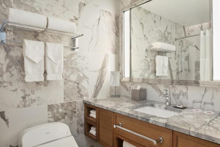 Baño de lujo con paredes de mármol y lavabo doble en Halepuna Waikiki by Halekulani