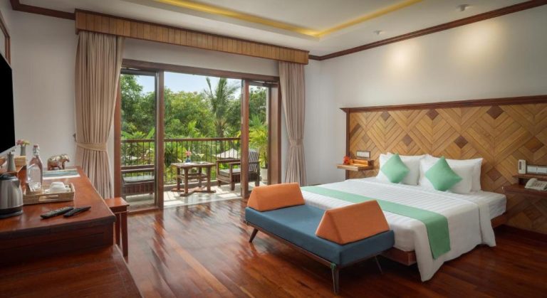 Habitación deluxe con cama doble, suelo de madera y balcón con vistas al jardín en Khmer House Resort