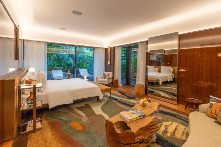 Suite de lujo con cama doble, mesa de madera natural y vistas al jardín tropical en Rosewood São Paulo