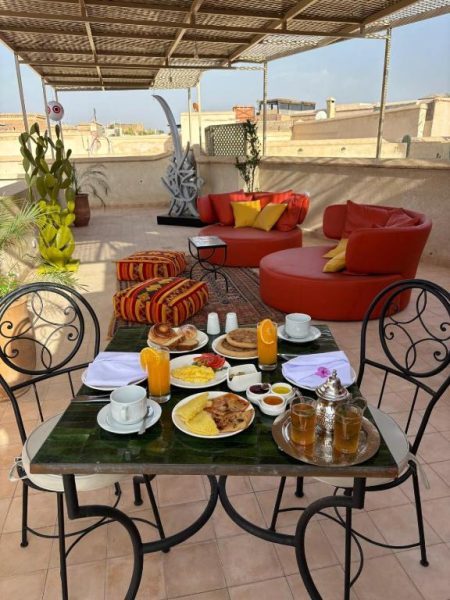 Desayuno tradicional marroquí en la terraza del Riad Timija con zumos, huevos y té