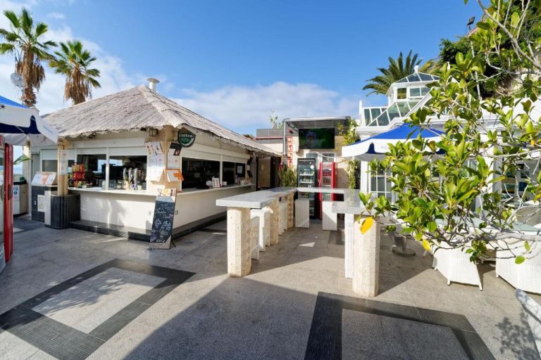 Bar terraza exterior con mesas de piedra y ambiente tropical del Aparthotel Maracaibo